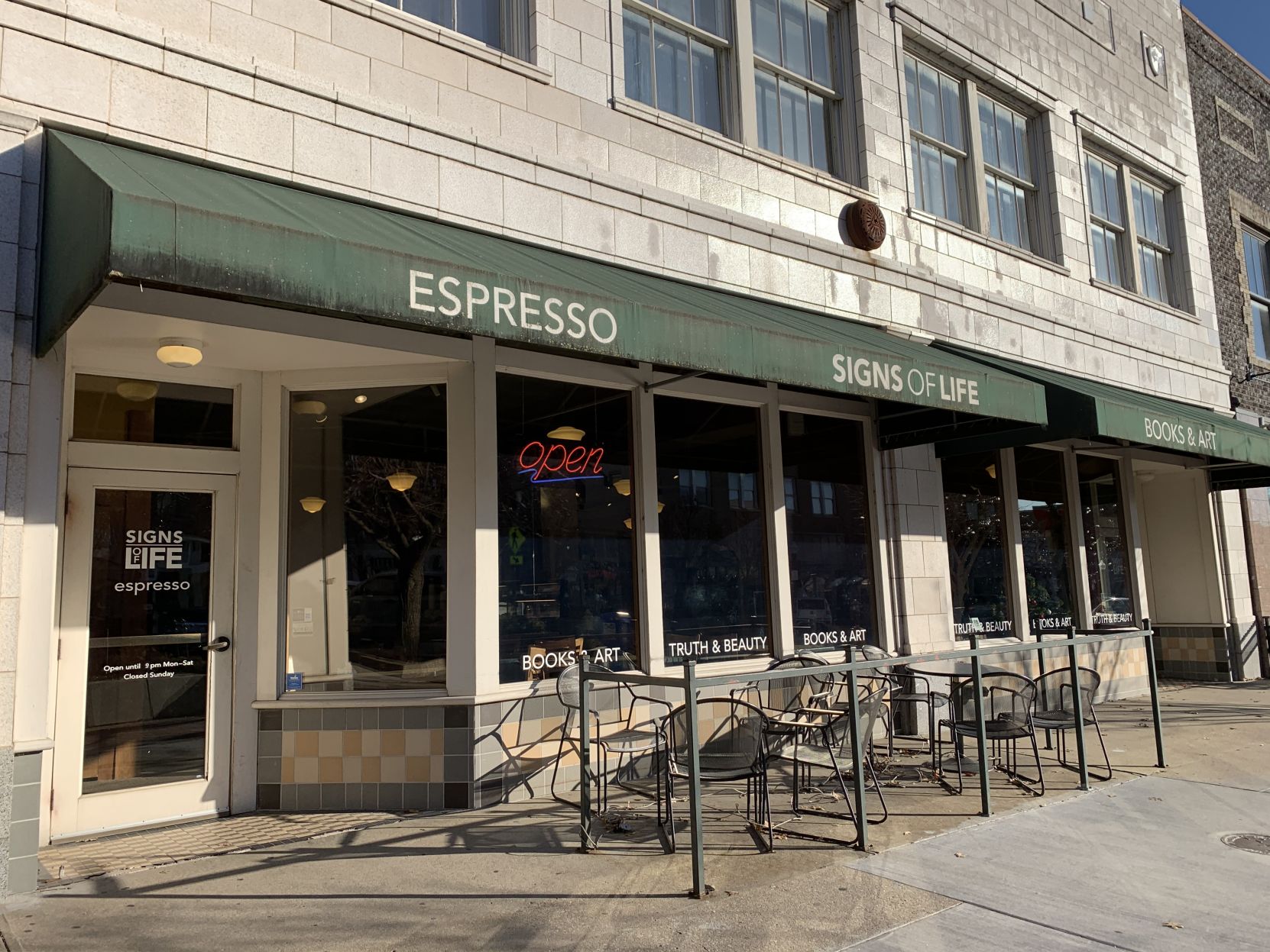 The awning over the entrance of Signs of Life features the words "espresso"